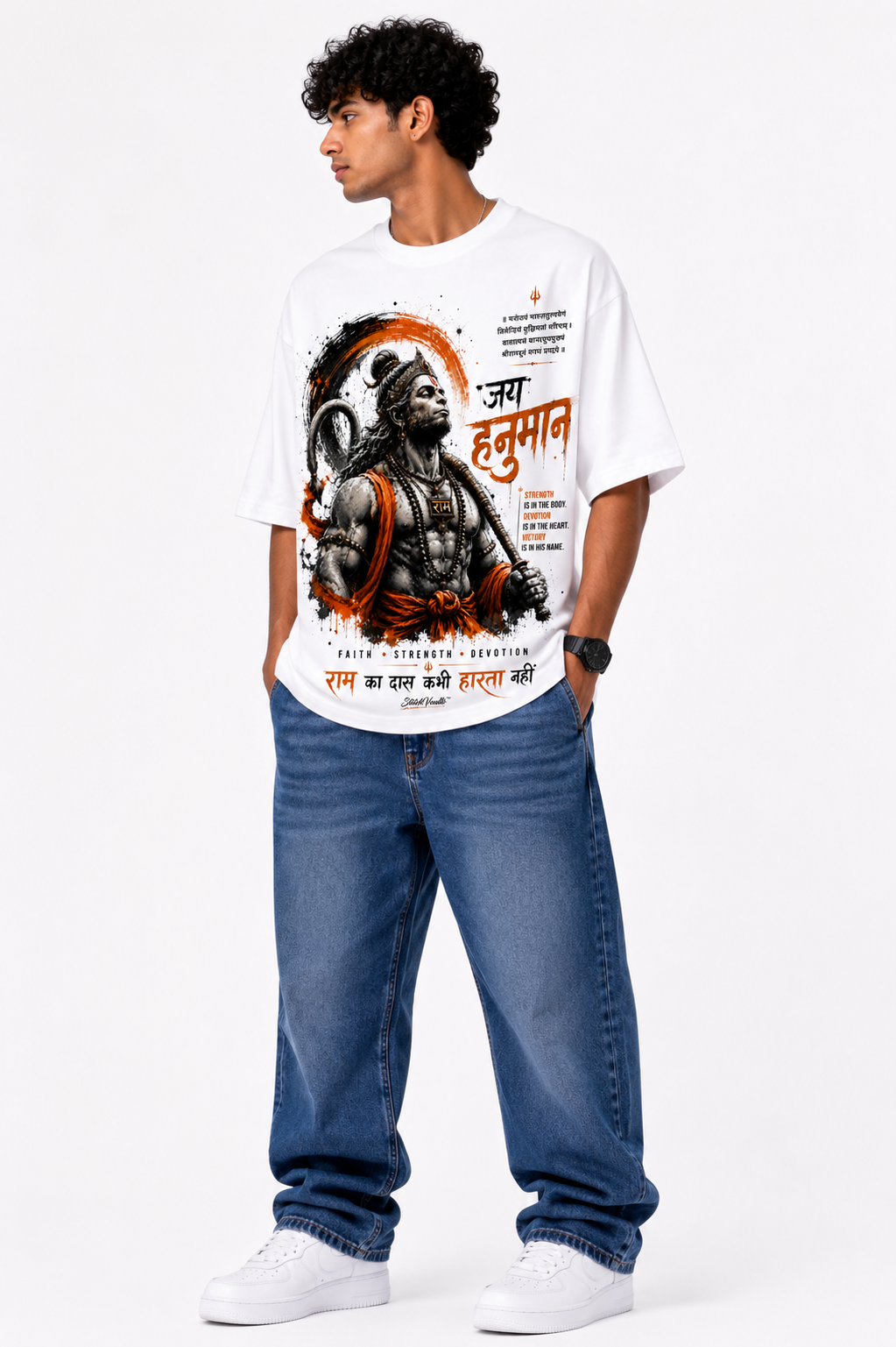 White oversized graphic T-shirt from the StitchVaults™ HANUMAN LEGACY™ Collection featuring a powerful Lord Hanuman illustration with bold Jai Hanuman typography, sacred devotional elements, and saffron-inspired artwork.