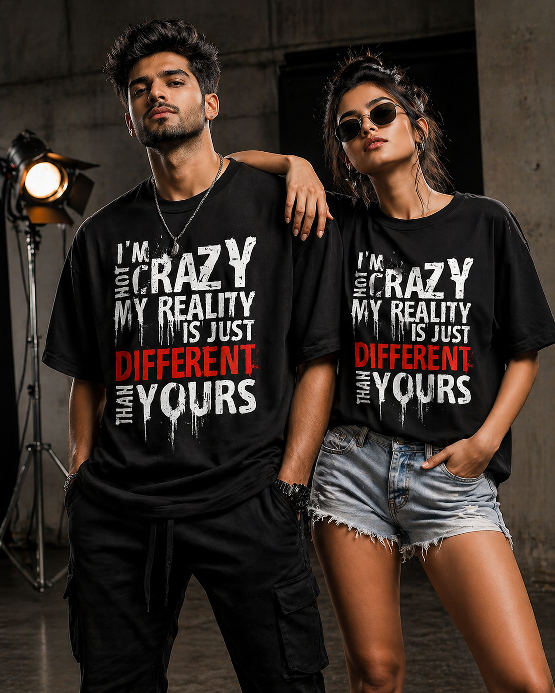 Indian male and female models wearing black graphic t-shirts with bold “I’m not crazy my reality is different than yours” quote in a studio photoshoot setting